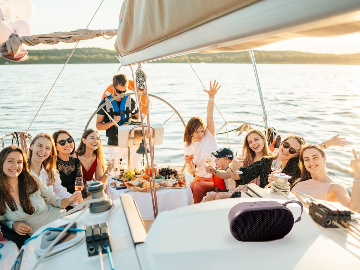 Group of friends enjoying music from a portable speaker on a boat